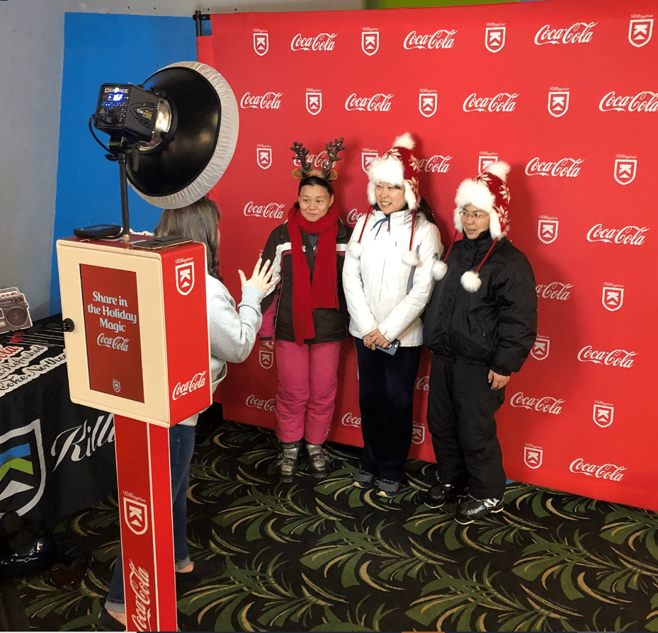 Photo booth set up at a Coca-Cola branded holiday event, children posing in Santa hats
